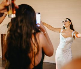 Noiva em branco e óculos празднует com amigas que a fotografam, braços abertos num gesto de alegria espontânea, instante de cumplicidade feminina, Humberto Barbosa Fotografia Santa Maria da Feira